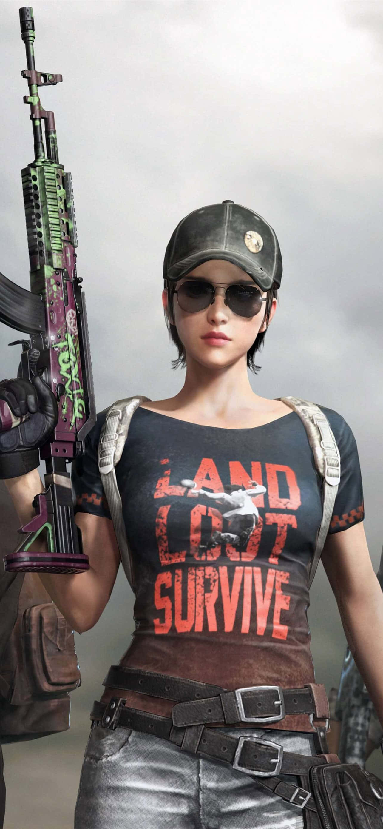 短髮酷炫PUBG女角色 壁紙 — 一名身穿戰術裝備的女兵，在朦朧的戰場背景下，手持一把佈滿塗鴉的步槍。