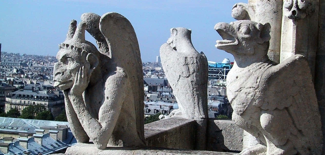 Gothic Architecture 桌布 壁紙 — 石像鬼有翅膀和兇猛的表情，棲息在大教堂屋頂上，俯瞰著晴朗藍天下的巴黎屋頂。