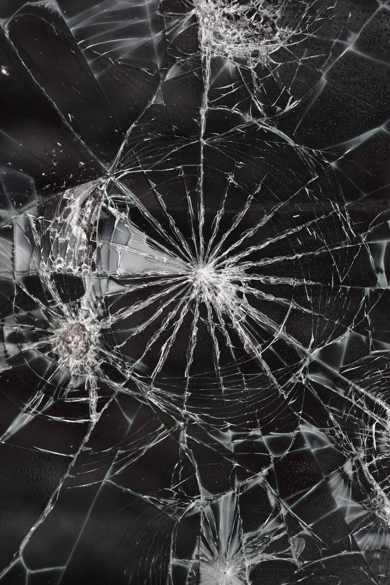 特寫破碎玻璃，在深色表面上呈現蜘蛛網狀裂紋。