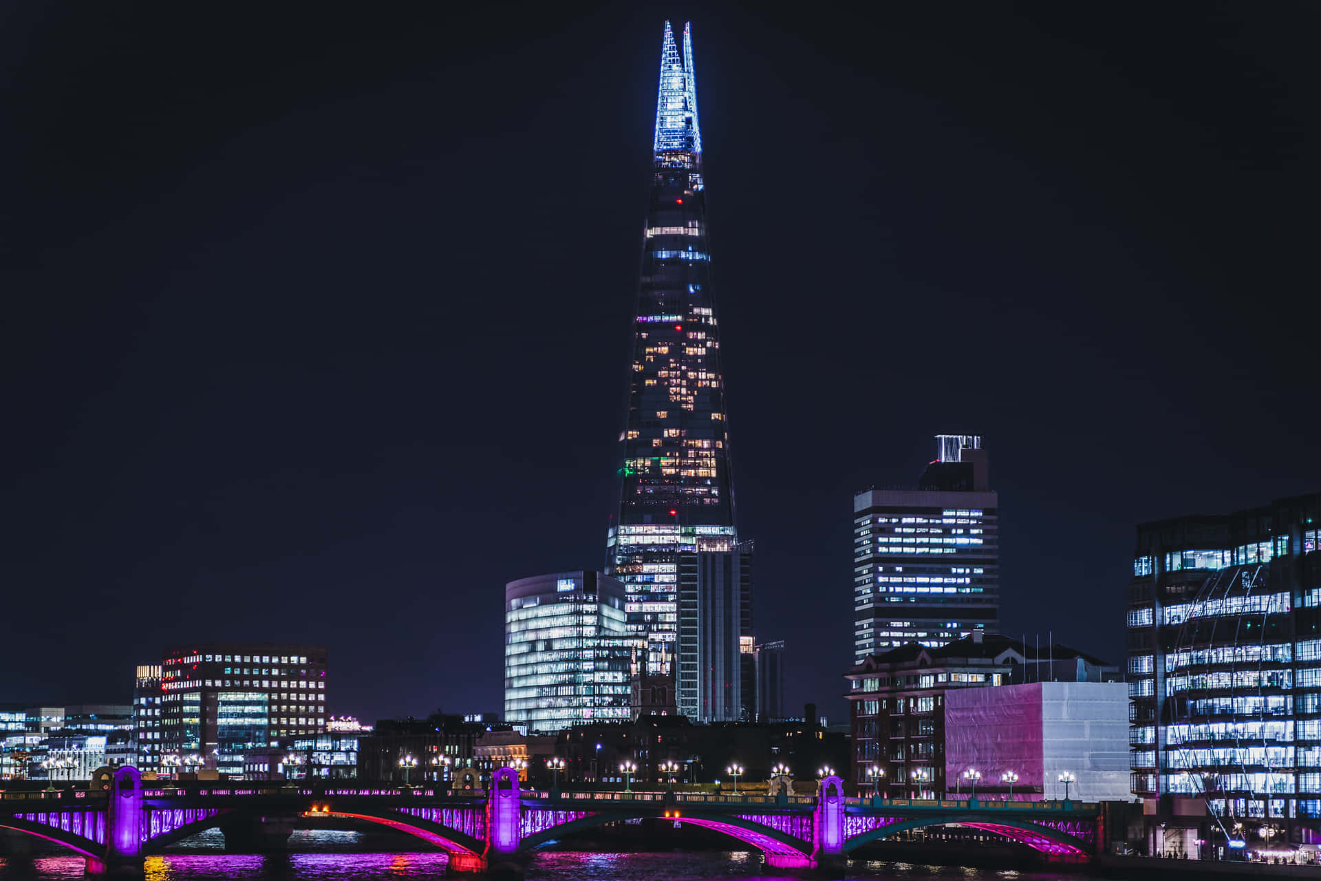 倫敦夜景城市風貌，展示碎片大廈和河上紫色燈光橋樑。