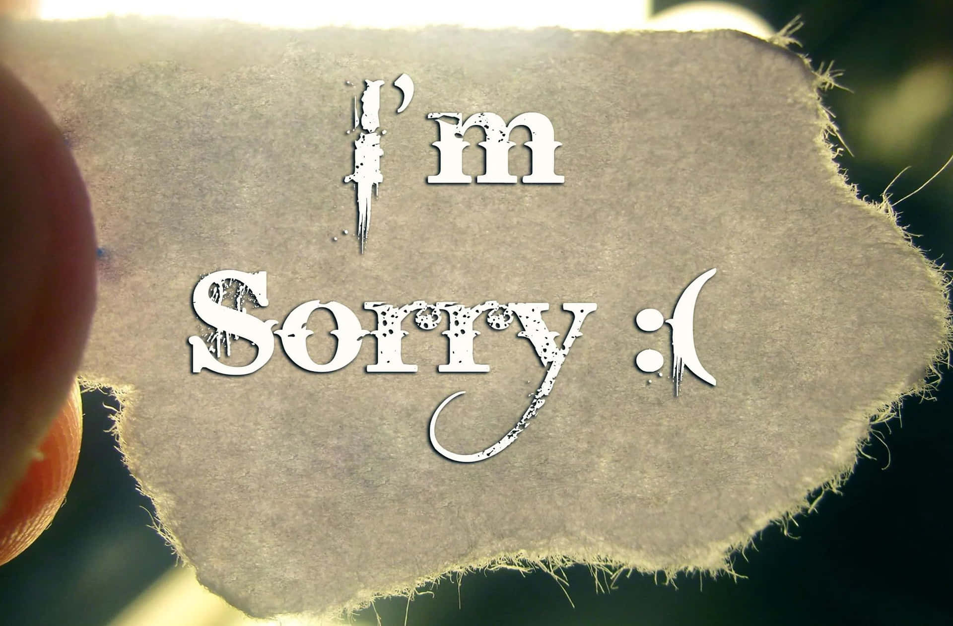 一隻手拿著一張破紙，上面用白色寫著「I'm Sorry :」的訊息。