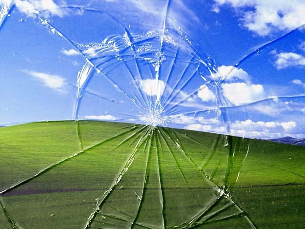 cracked 桌布 壁紙 — 碎裂的玻璃視野展現出下方充滿活力的藍天、蓬鬆的白雲和鬱鬱蔥蔥的綠色山坡。