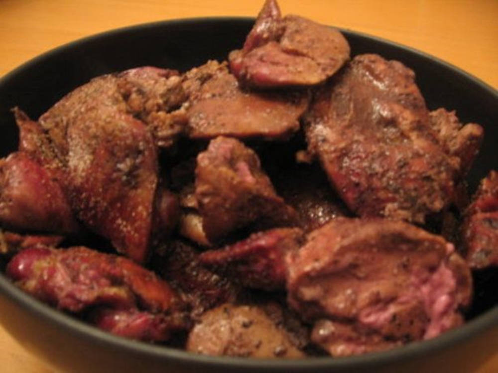 黑色碗中的調味烤過的肉塊，放在木桌上。