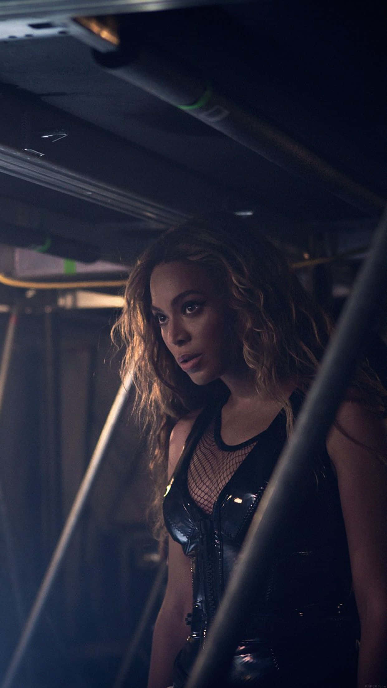 碧昂絲展現迷人姿態 壁紙 — Beyoncé 喺一個由金屬條框住嘅昏暗工業空間入面，強烈地凝視。