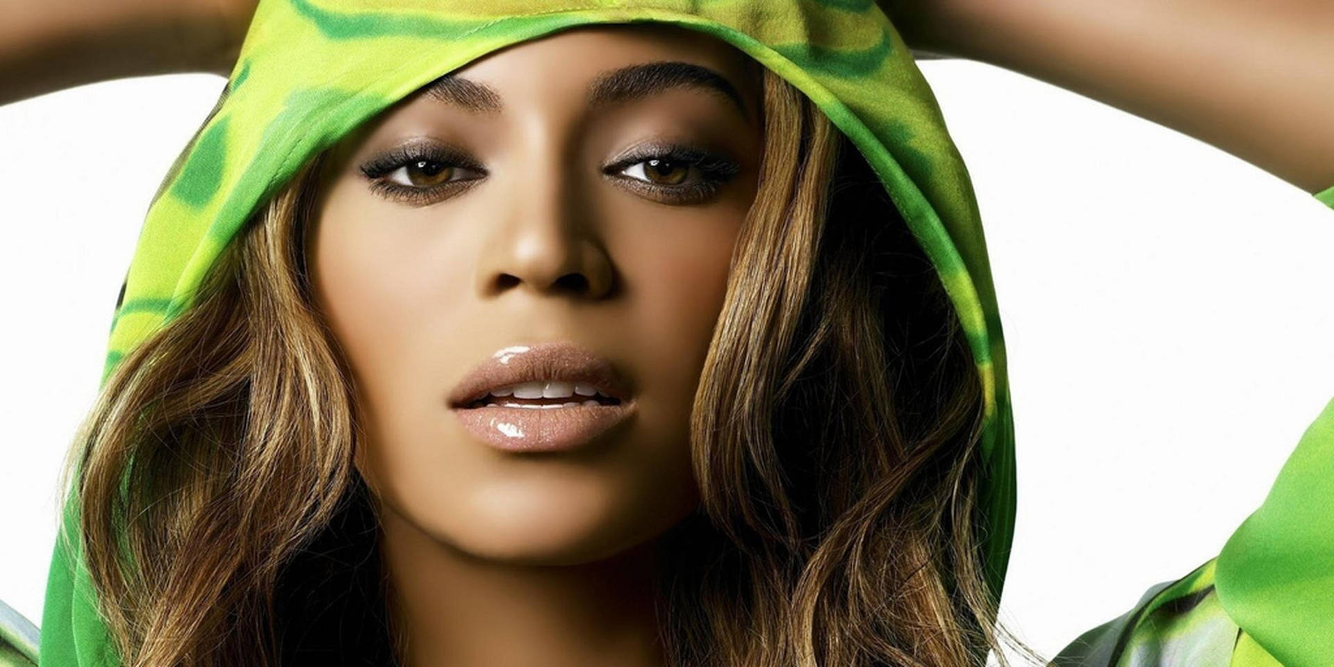 Beyoncé 穿著綠色紮染連帽衫，雙手舉在腦後。