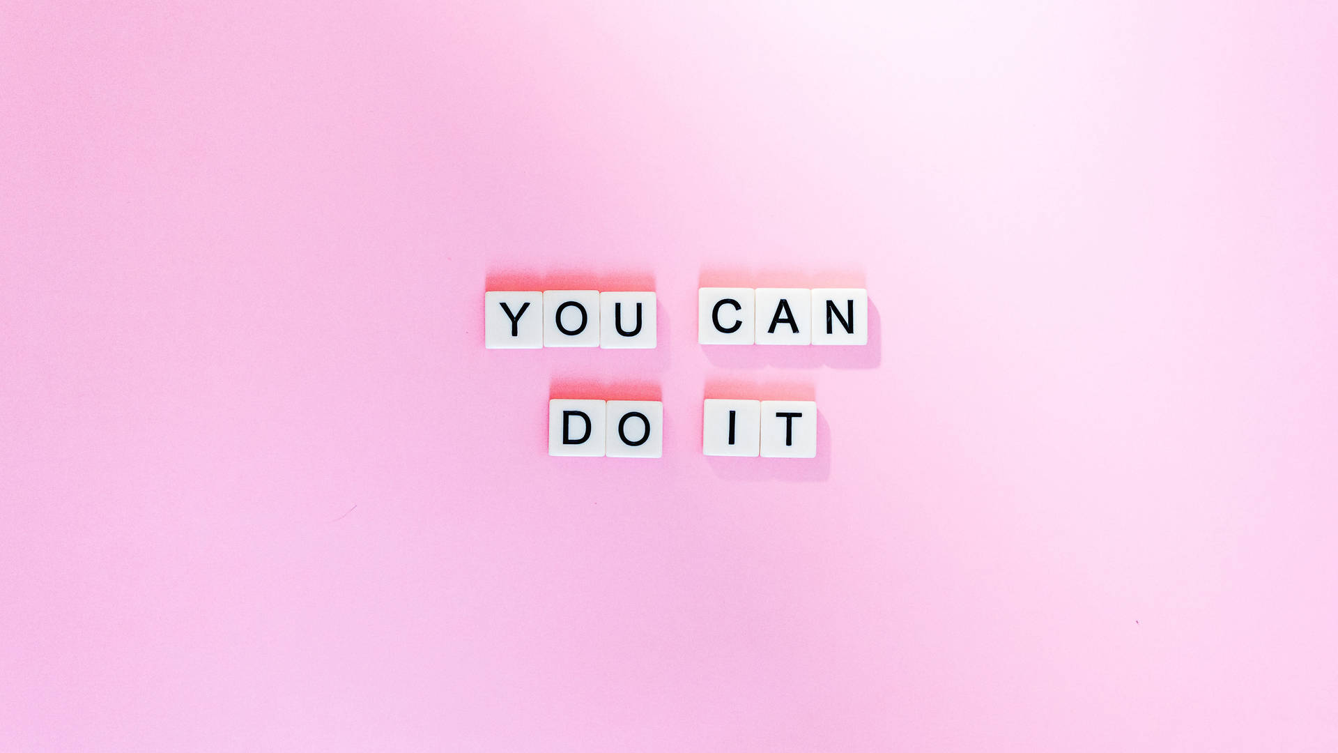 在粉紅色背景上用白色字母瓷磚拼出的勵志短語 you can do it。