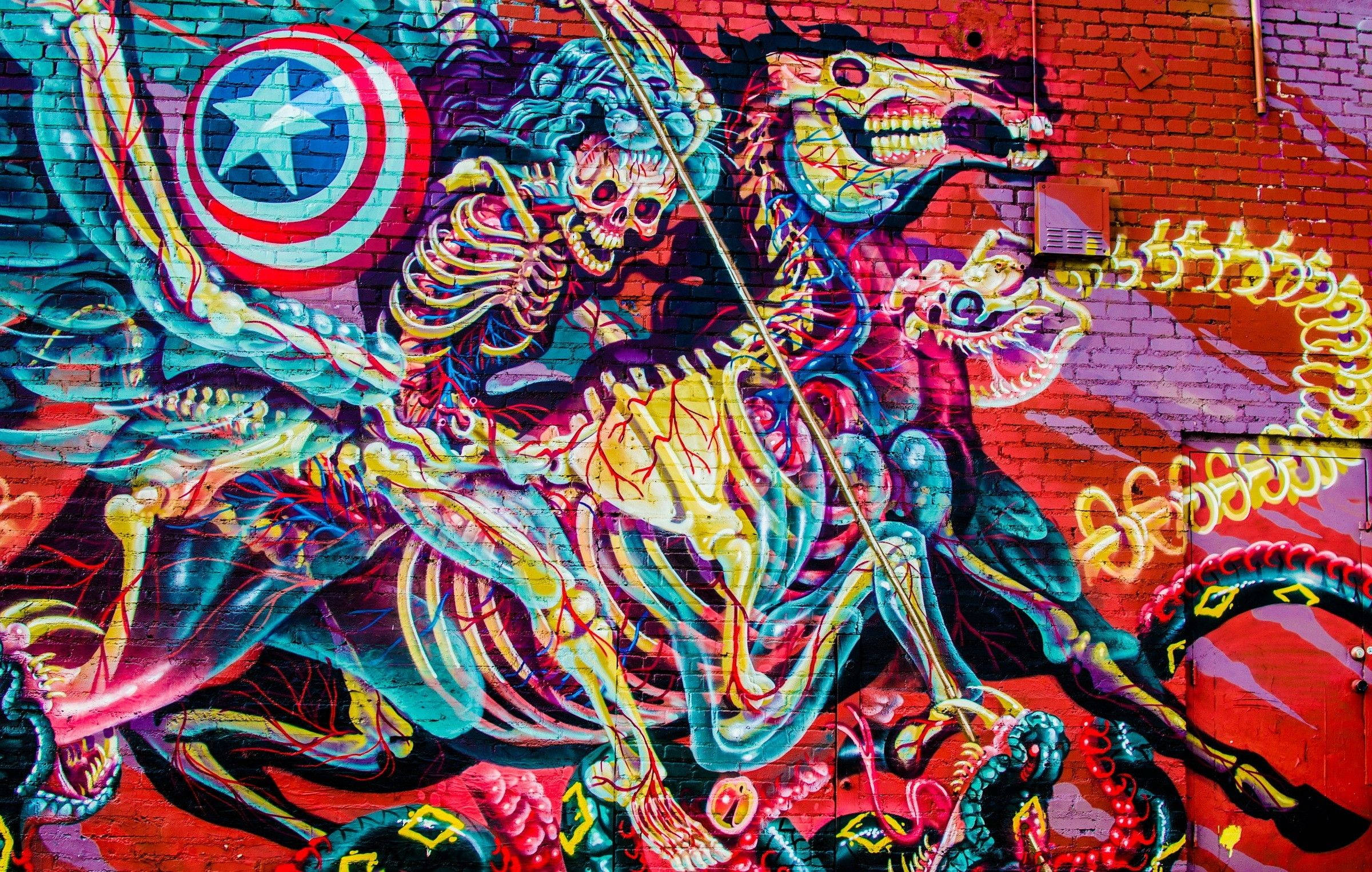 塗鴉 桌布 壁紙 — 磚牆上充滿活力的塗鴉壁畫描繪了一個騎著馬、手持盾牌和長矛的骷髏戰士，置身於混亂多彩的圖案之中。