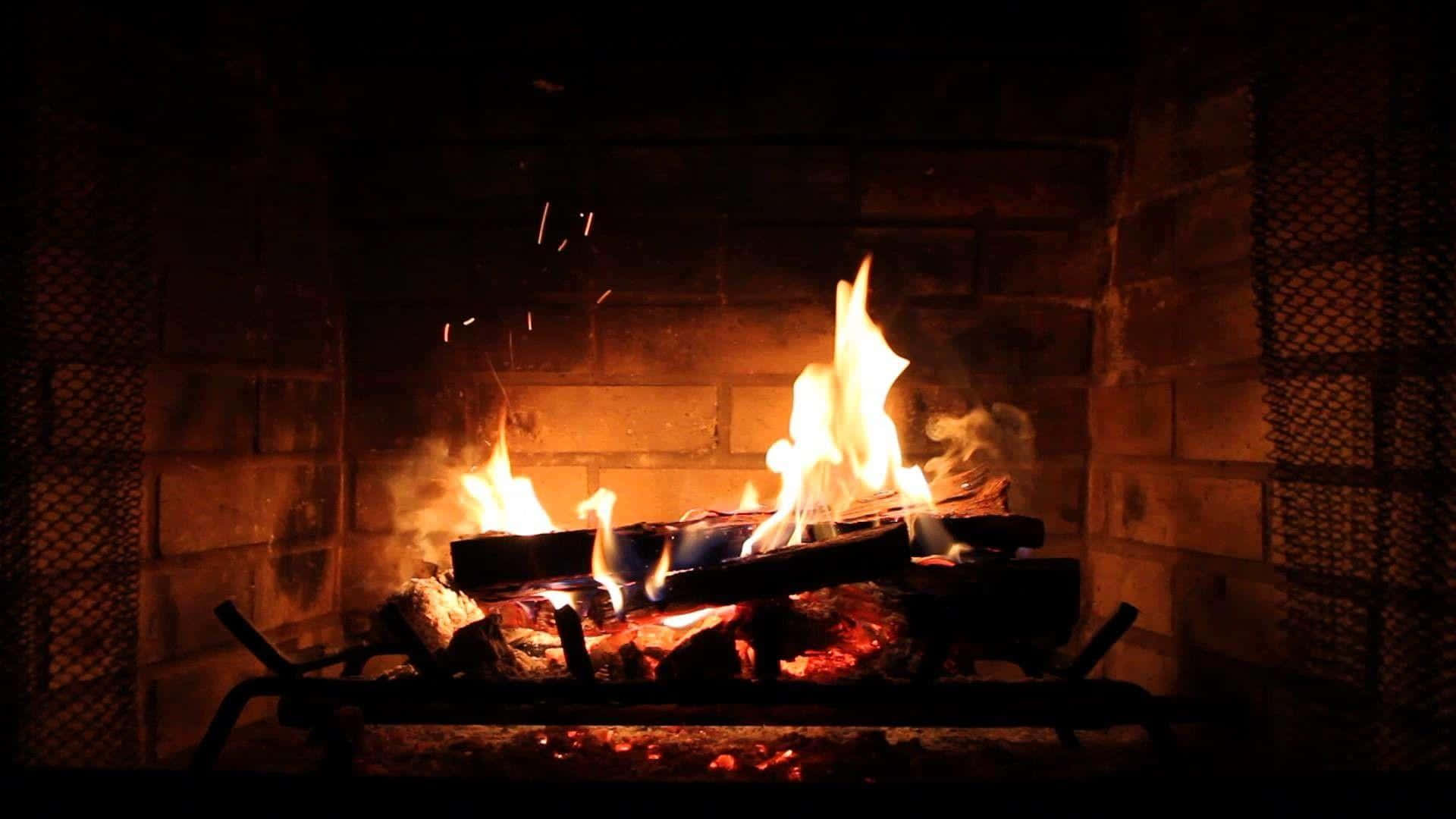 Autumn Fireplace 桌布 壁紙 — 磚砌壁爐中熊熊燃燒的火焰發出噼啪聲，將溫暖的橙色光芒投射到周圍的石頭和金屬網上。