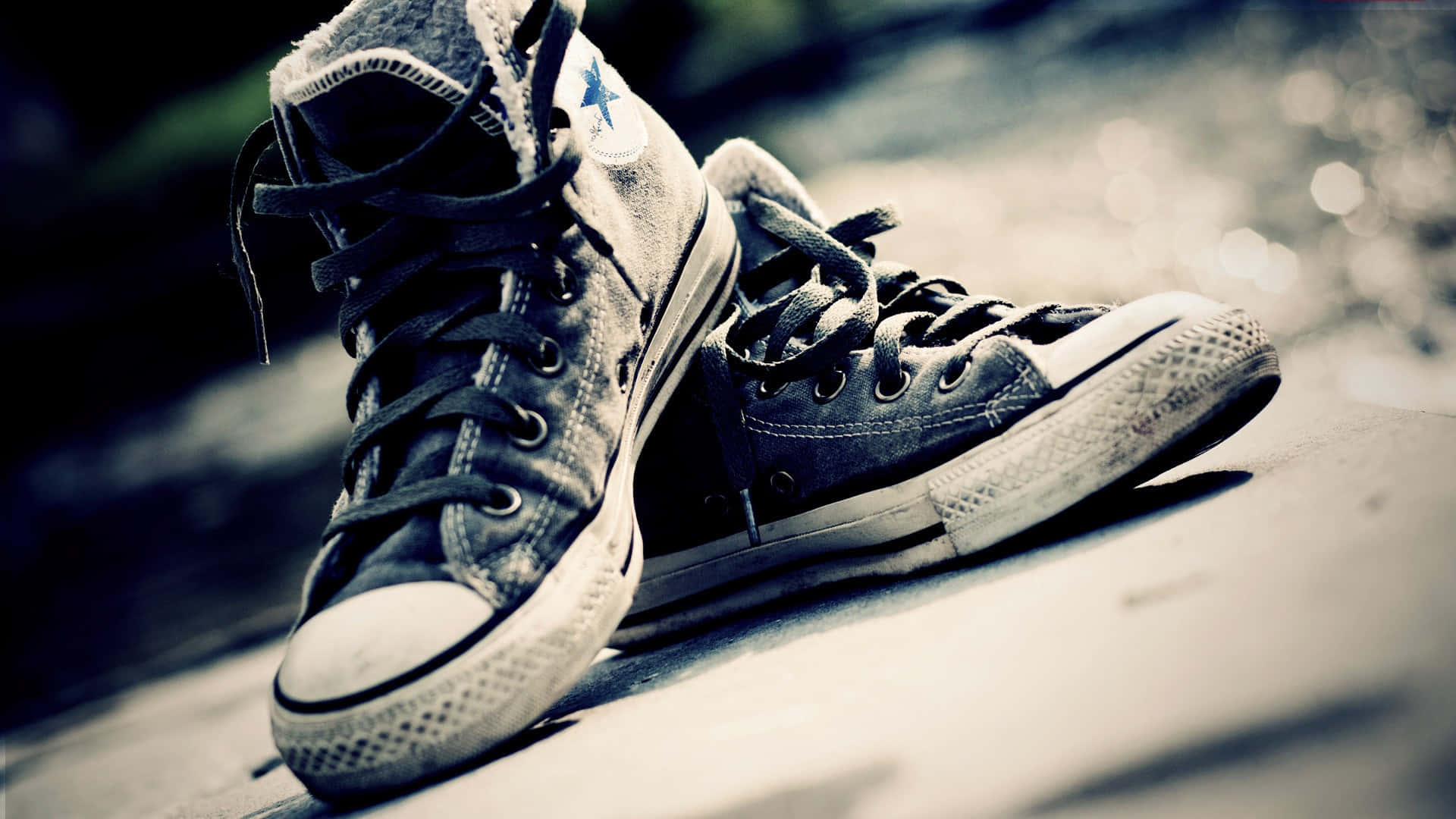Footwear Design 桌布 壁紙 — 磨損的高筒運動鞋放在陽光普照的行人路上，景深淺，色調復古。