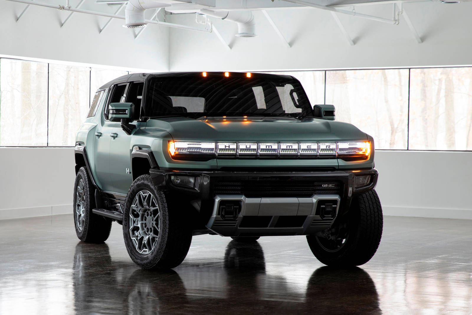 綠色Hummer EV SUV在明亮的白色工作室中，地板具有反射效果。
