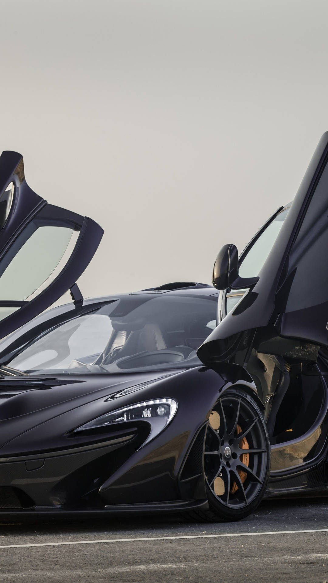 黑色McLaren跑車打開鷗翼車門停泊喺瀝青路上。