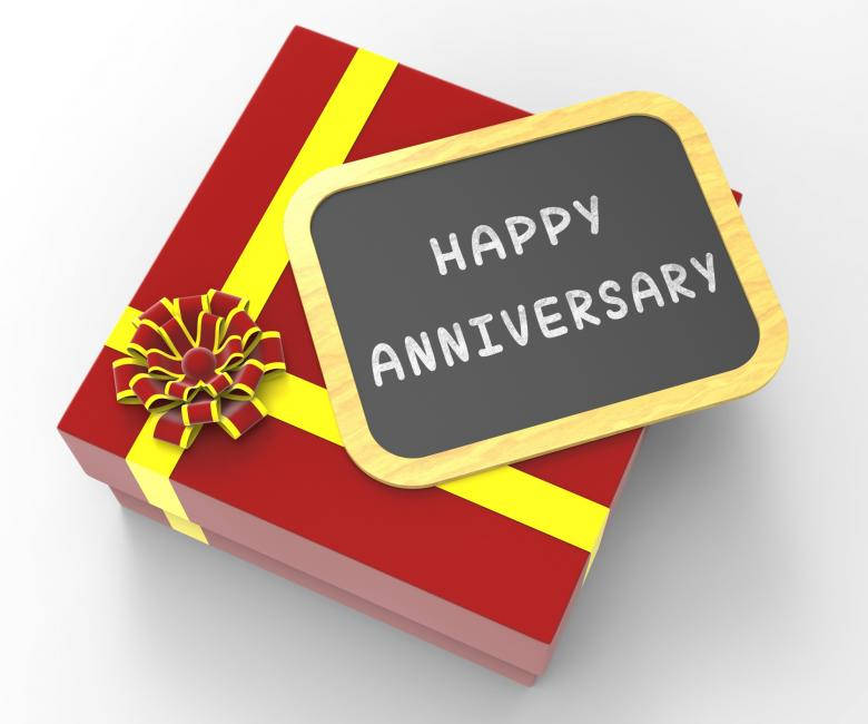 紅色禮物盒，配有黃色絲帶和黑板標牌，上面寫著 happy anniversary。