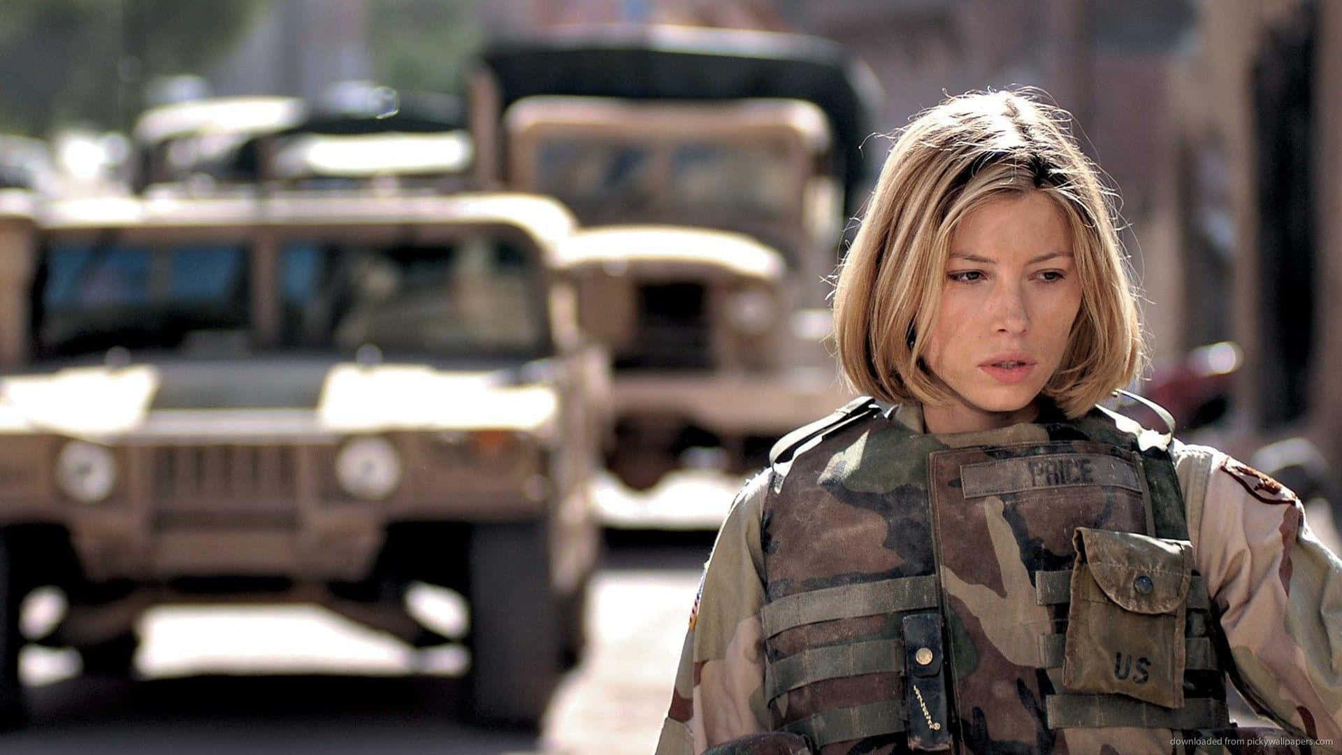 身穿迷彩服的女兵站在街上，身後有軍用車輛。