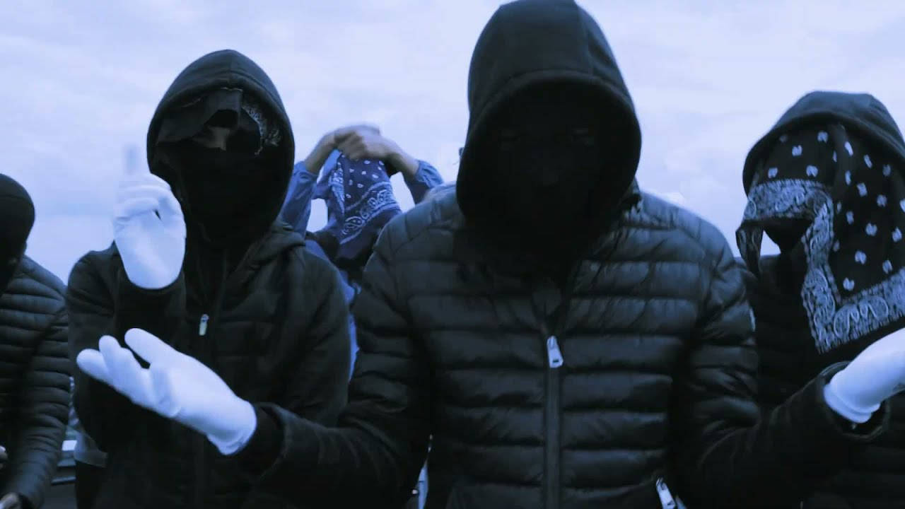 UK Drill Free For Profit 壁紙 — 神秘嘅 hooded 人物穿着深色外套同白色手套企喺冷色調嘅戶外場景中。