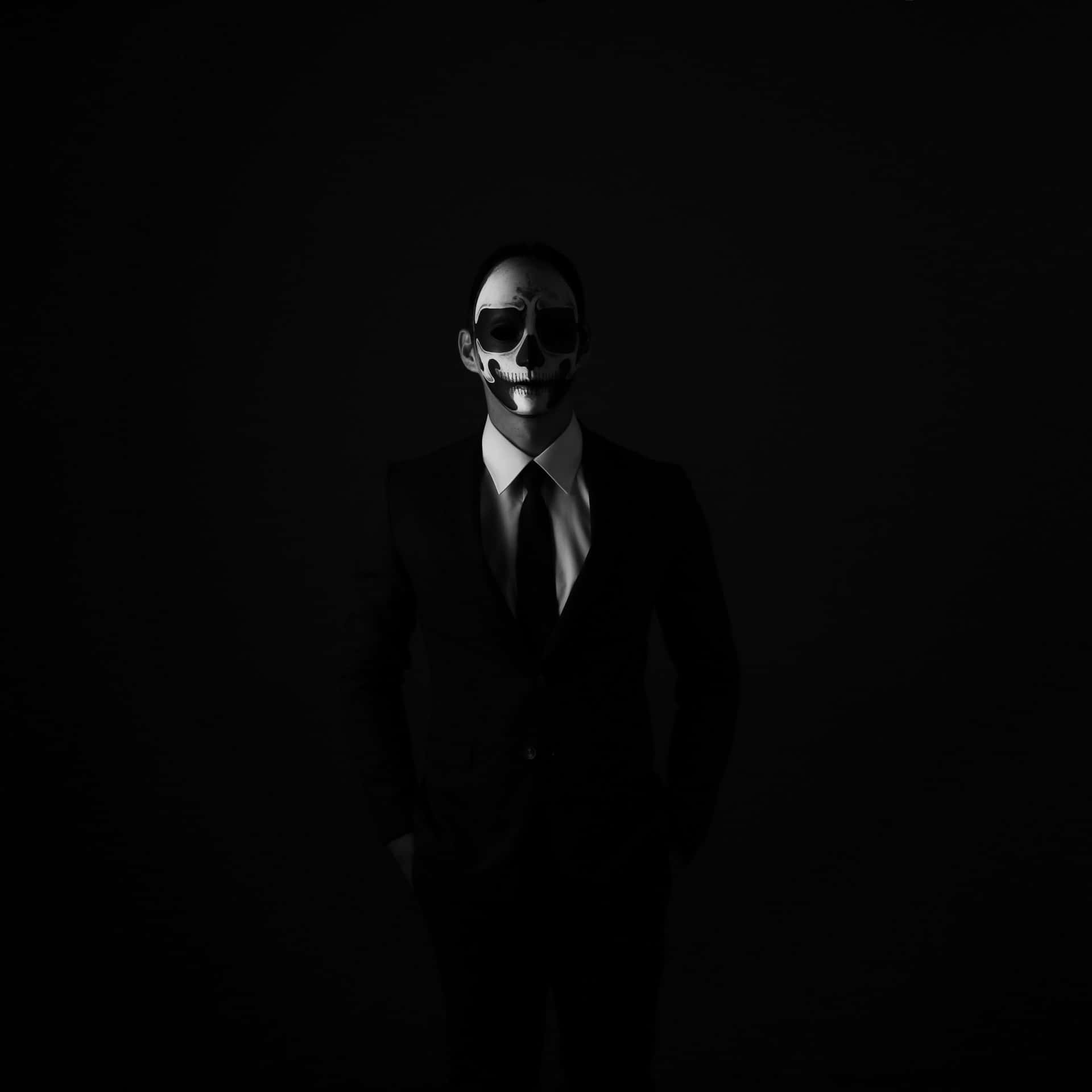 穿西裝的男子，臉上畫著骷髏圖案，在昏暗的攝影棚燈光下