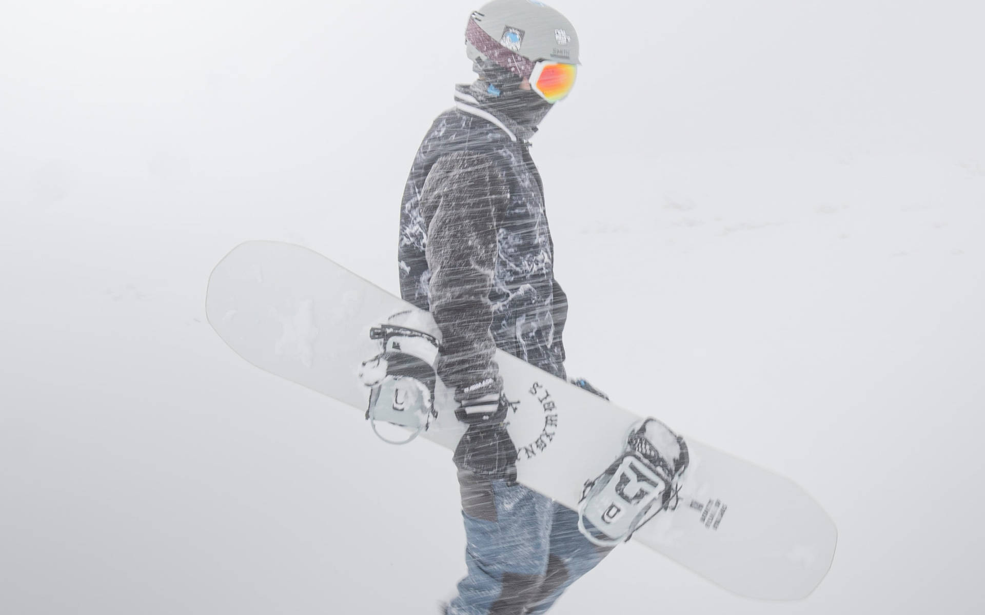 滑雪板手在大雪中行走，腋下夾著滑雪板。