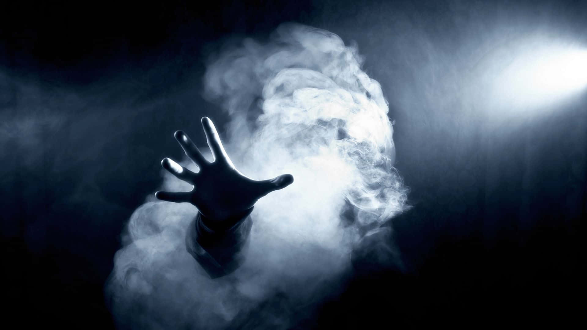 神秘煙霧薄紗 壁紙 — 一隻剪影手從旋轉的煙霧中浮現，在強烈的聚光燈下，背景黑暗。