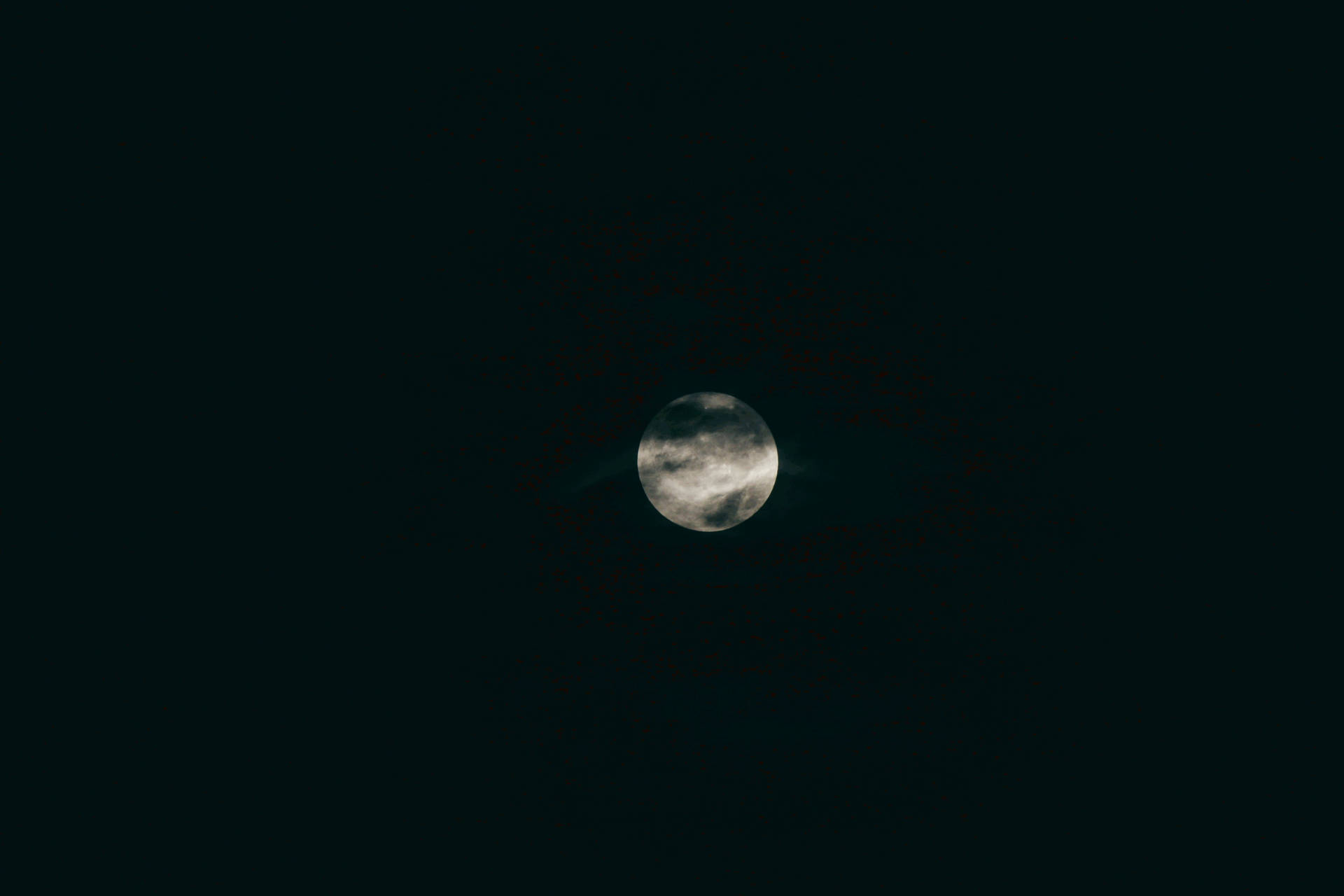 在黑暗的夜空中，月亮被雲層部分遮蓋。