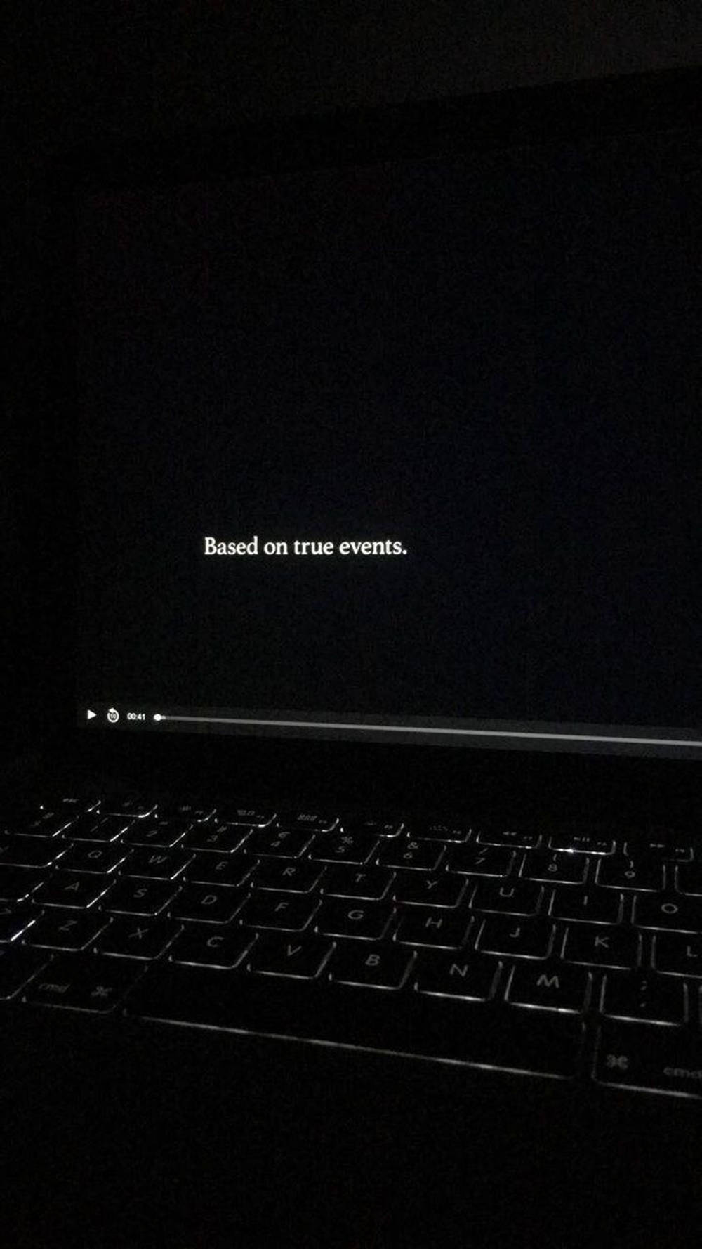 手提電腦屏幕顯示「Based on true events.」及黑暗中鍵盤。