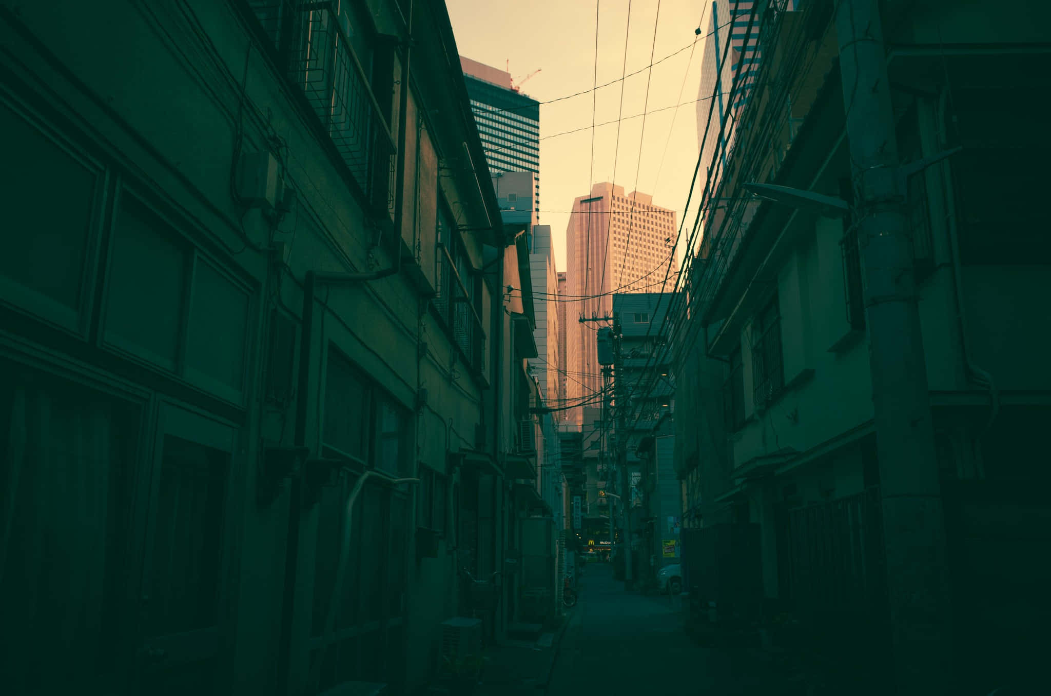 神秘黑暗巷弄 壁紙 — 一條狹窄的城市小巷，兩旁是舊建築，纏繞的電線通向沐浴在溫暖夕陽餘暉中的高聳摩天大樓。