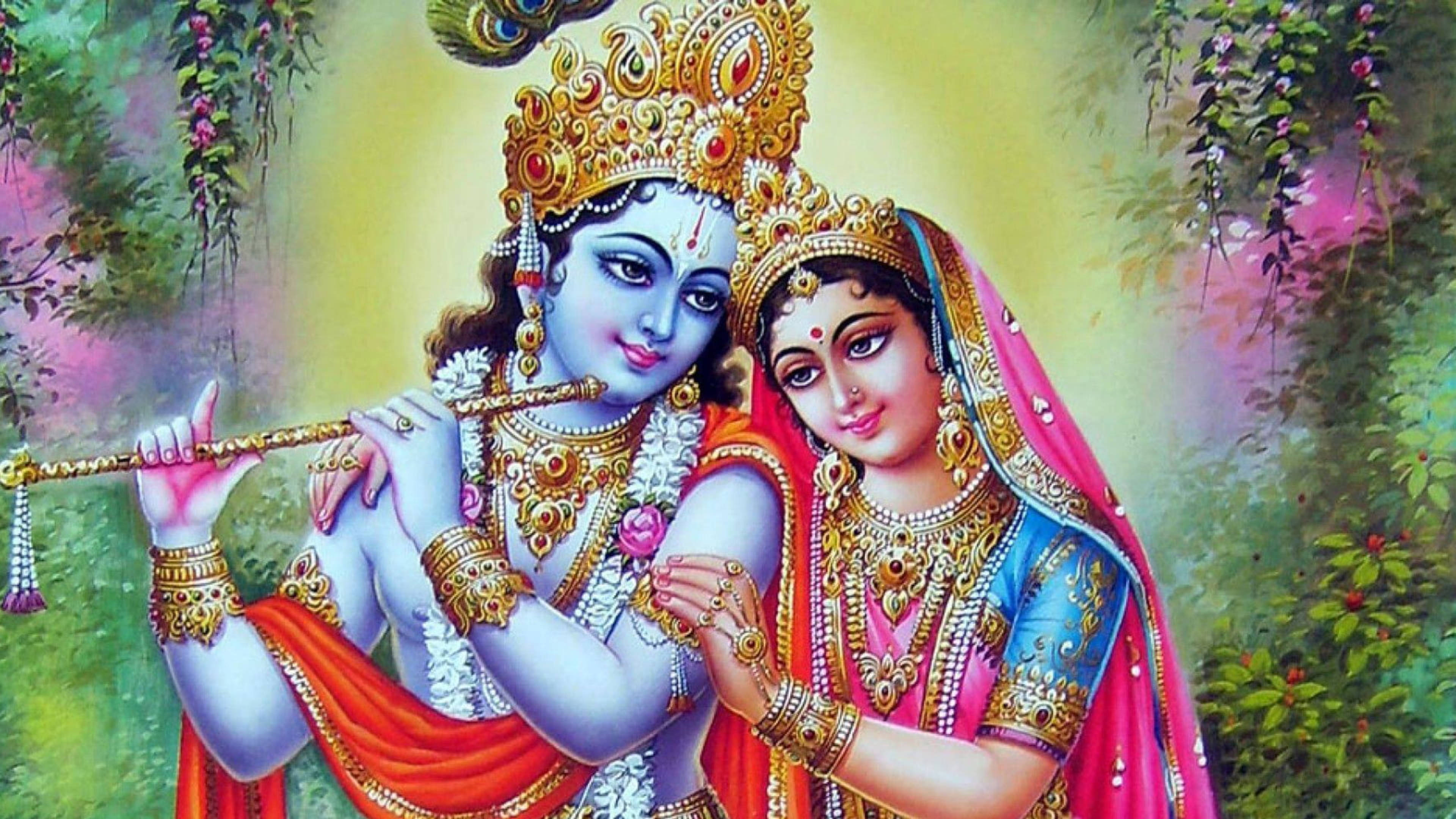 krishna ji 桌布 壁紙 — 神聖情侶克里希納和拉達，佩戴金色珠寶和鮮豔長袍，在繁茂的花園中分享親密時刻。