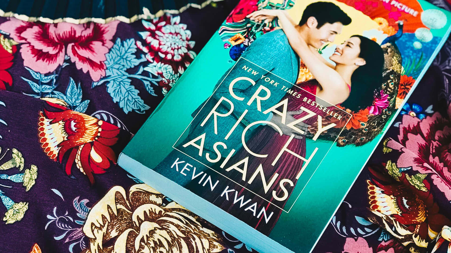 書《Crazy Rich Asians》在色彩繽紛的花卉布料背景上。