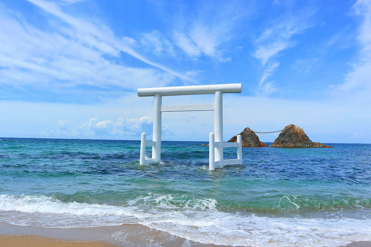 福岡海洋風景 壁紙 — 一座寧靜的白色鳥居部分浸沒在碧綠的海水中，上方是晴朗的藍天，點綴著縷縷白雲。