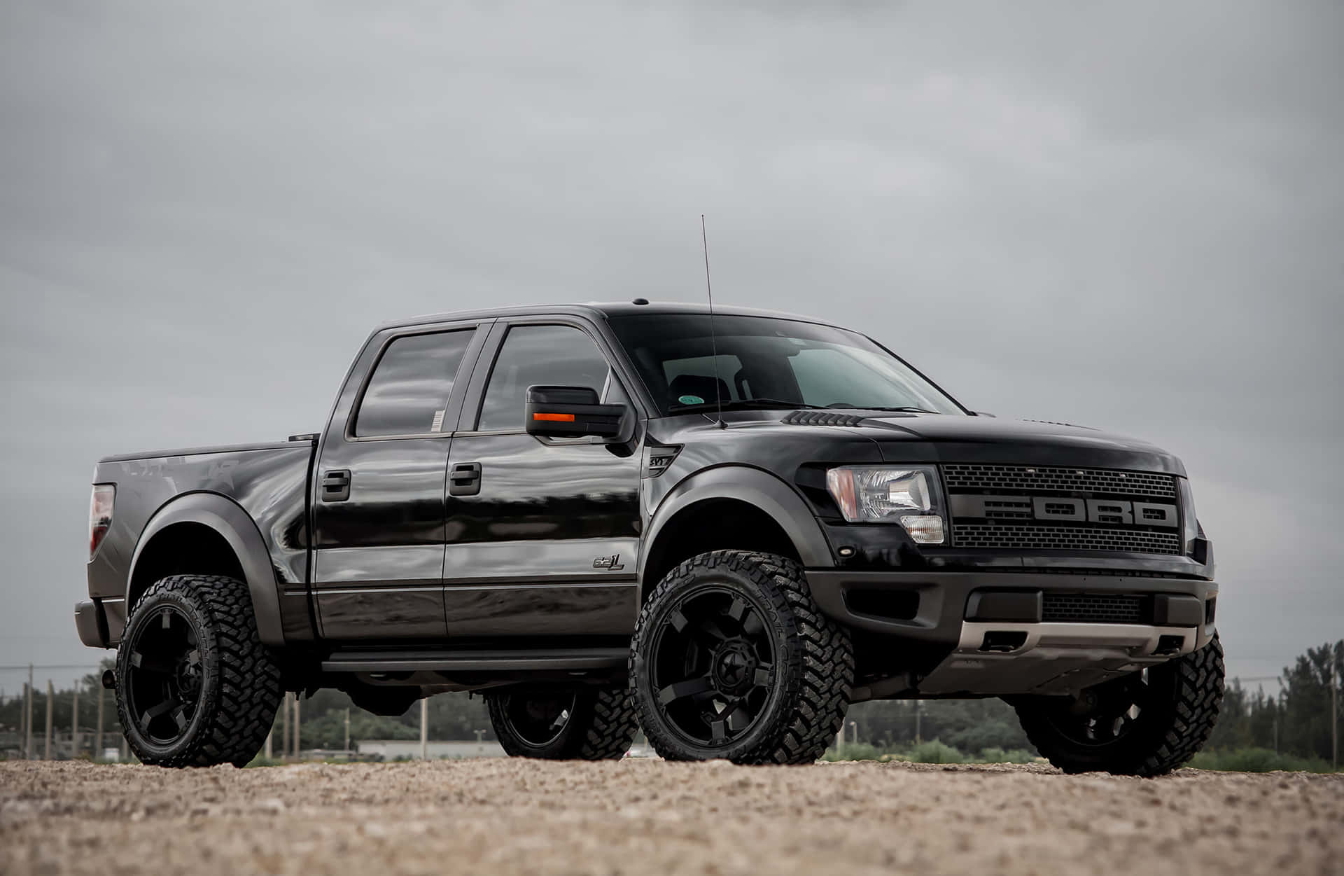 黑色福特F-150 Raptor pickup貨車喺碎石上，背景係陰天天空。