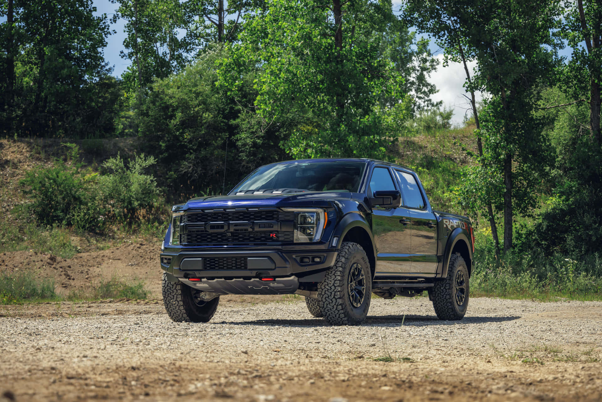 黑色福特 F-150 Raptor 貨車停在森林中的碎石路上。