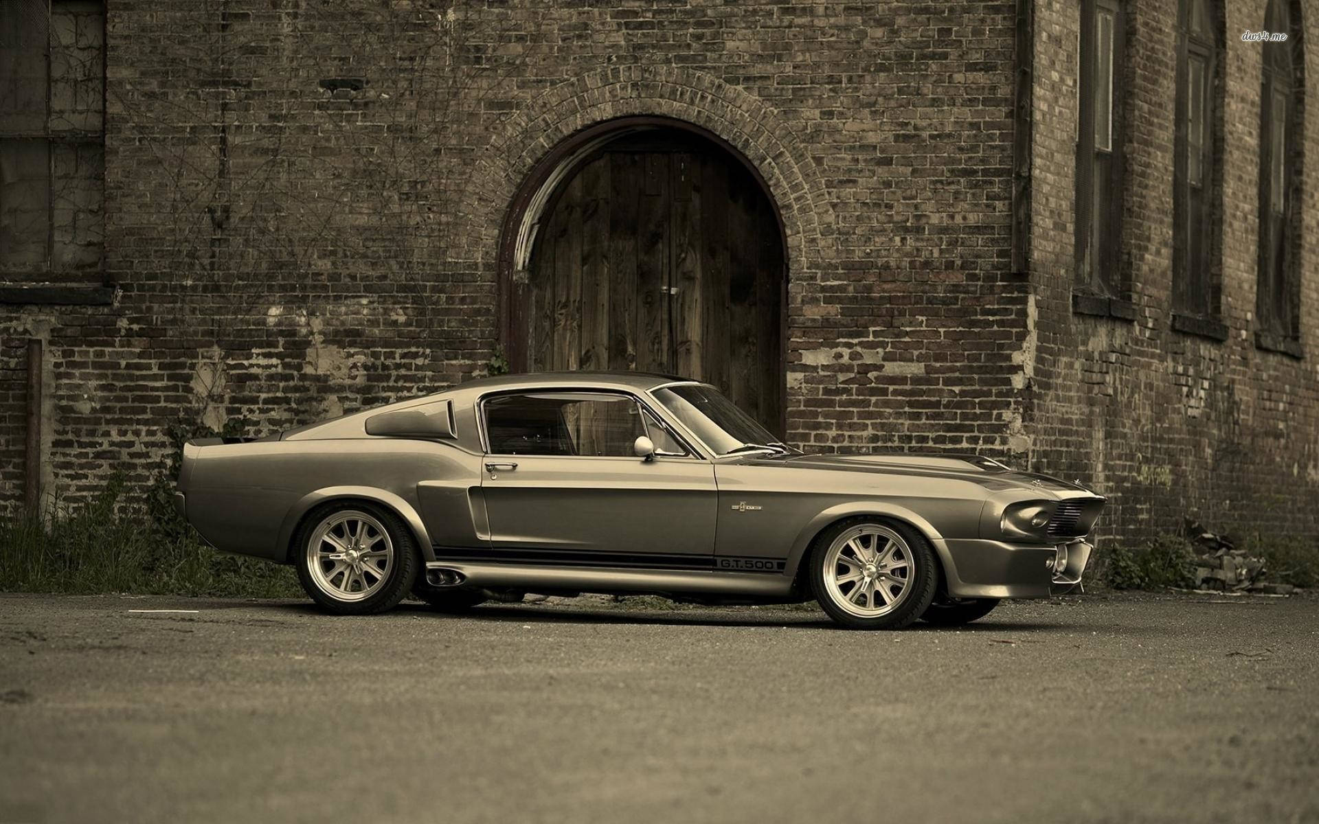 銀色經典Shelby GT350肌肉車停泊在舊磚建築前。