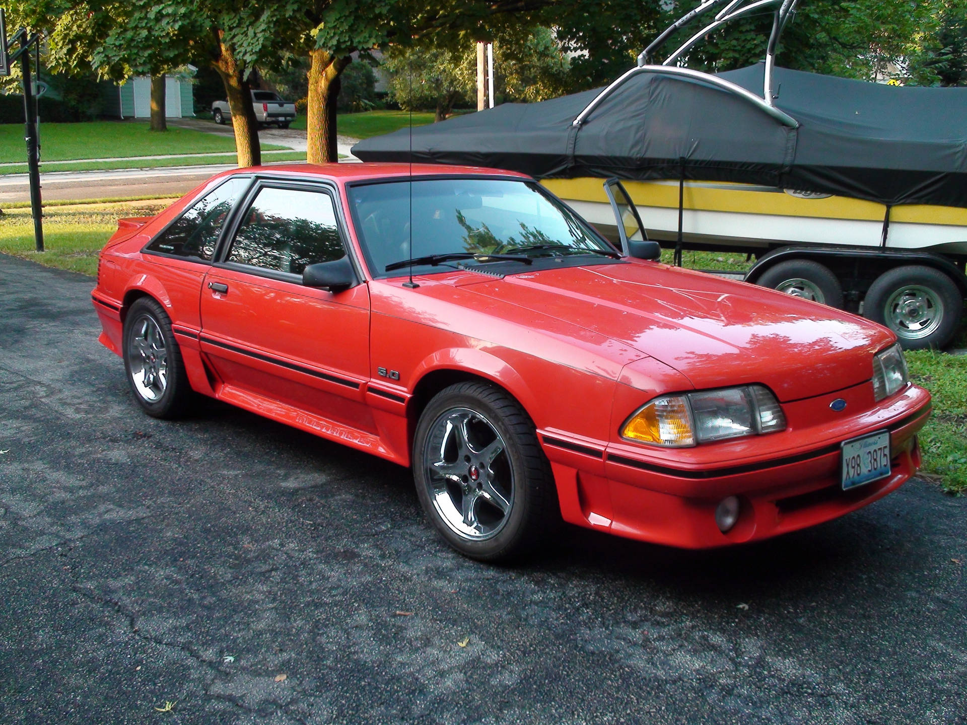 紅色福特 Mustang SVO 停喺車道上，旁邊係一個船拖車。