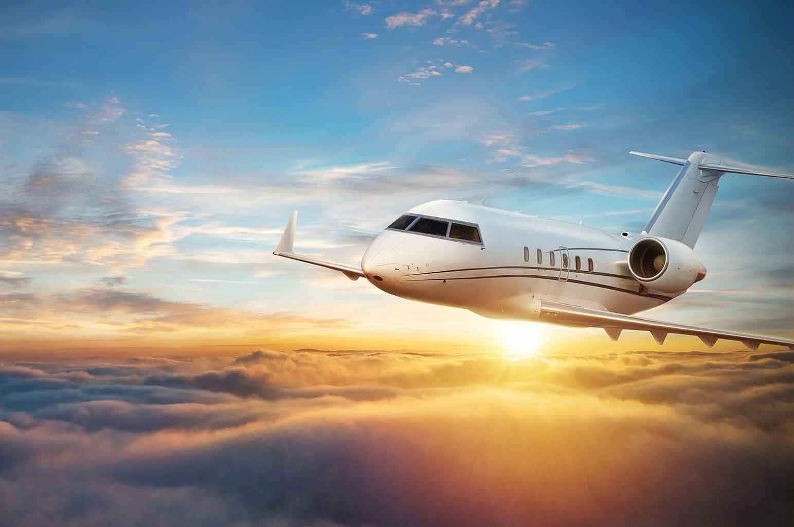 白色私人飛機在日出雲層上方飛行