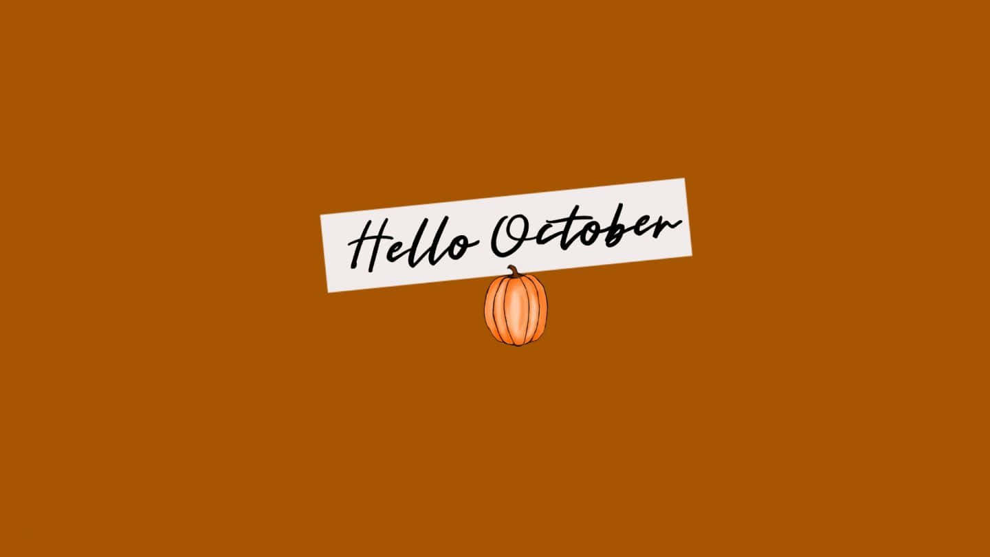 秋日之美，橙、紅、黃的秋日色彩 壁紙 — 一個白色橫幅上以草書寫著 Hello October，懸掛在一個小橙色南瓜上方，背景為純鏽色。