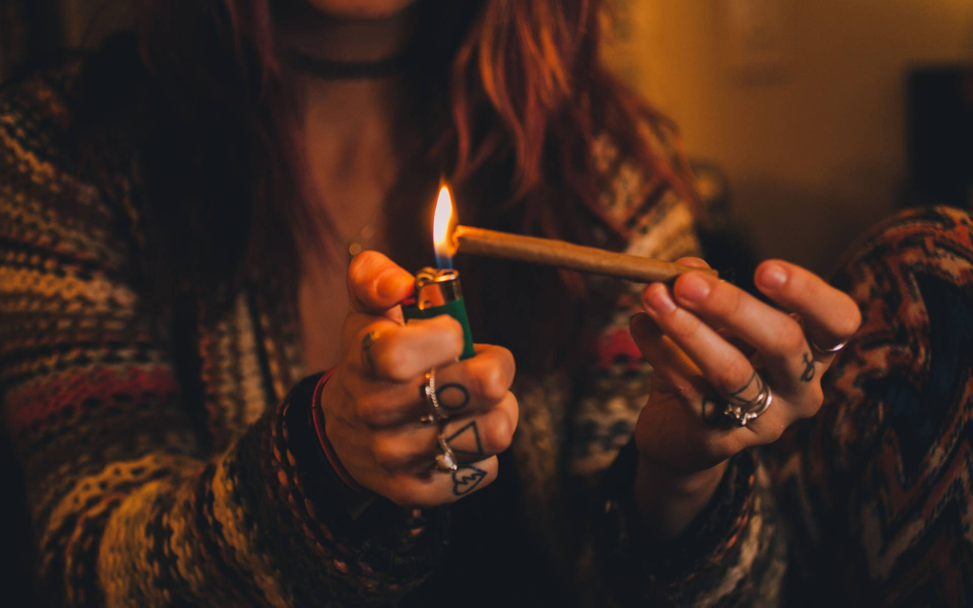 室內用綠色打火機點燃大麻煙的手部特寫。