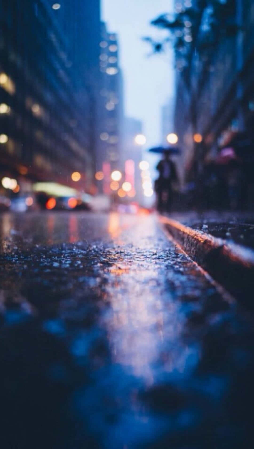 雨夜城市街道，閃爍的倒影和一個撐傘的人。