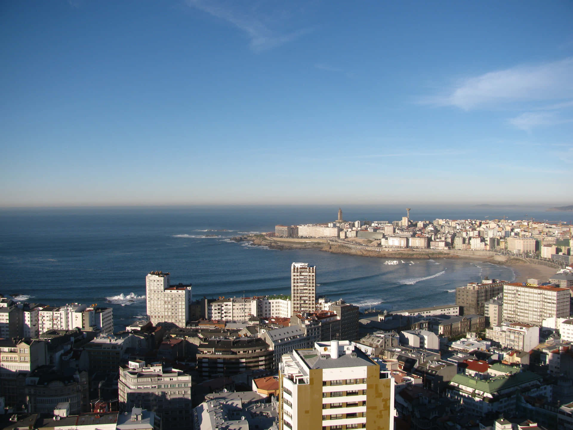 沿海城市景觀，建築物沿著沙灘和海洋分佈，天空清澈湛藍。