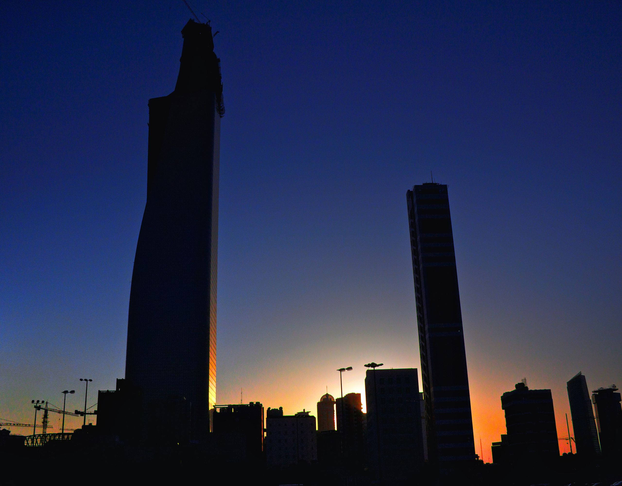 科威特建築剪影 壁紙 — 剪影般的摩天大樓在夕陽橙與深藍色調的漸變天空中升起。