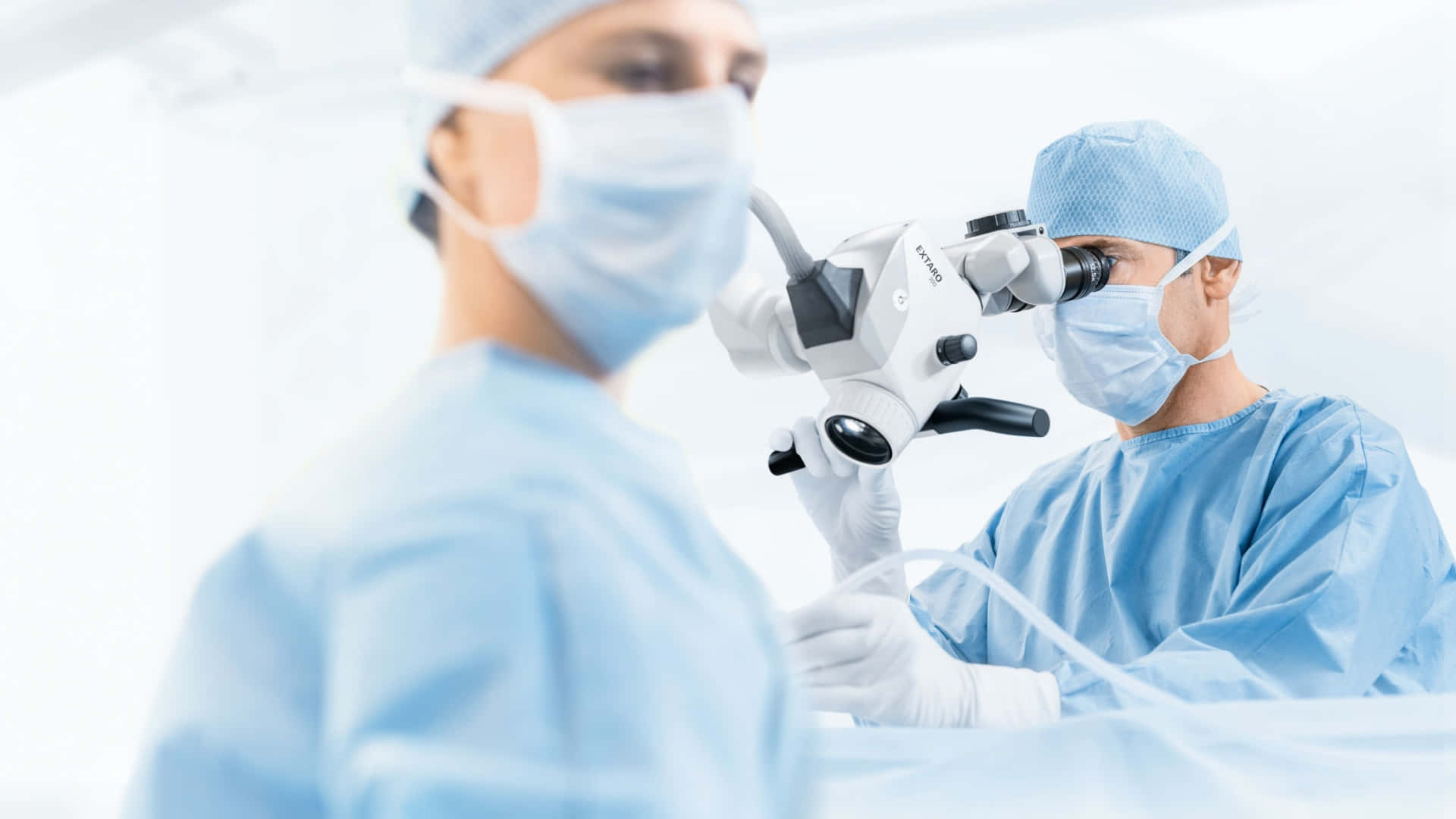兩名戴著口罩、身穿藍色手術服的外科醫生正在使用醫療設備進行手術。