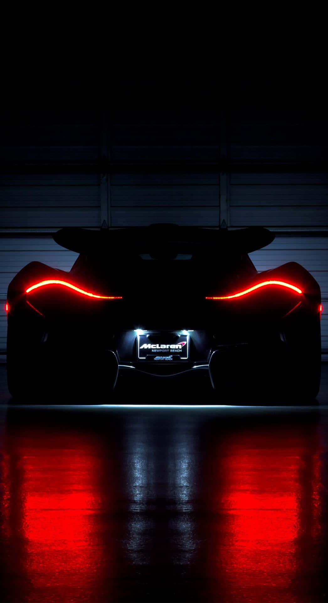 夜間McLaren超級跑車的紅色尾燈反射在潮濕的車庫地板上。