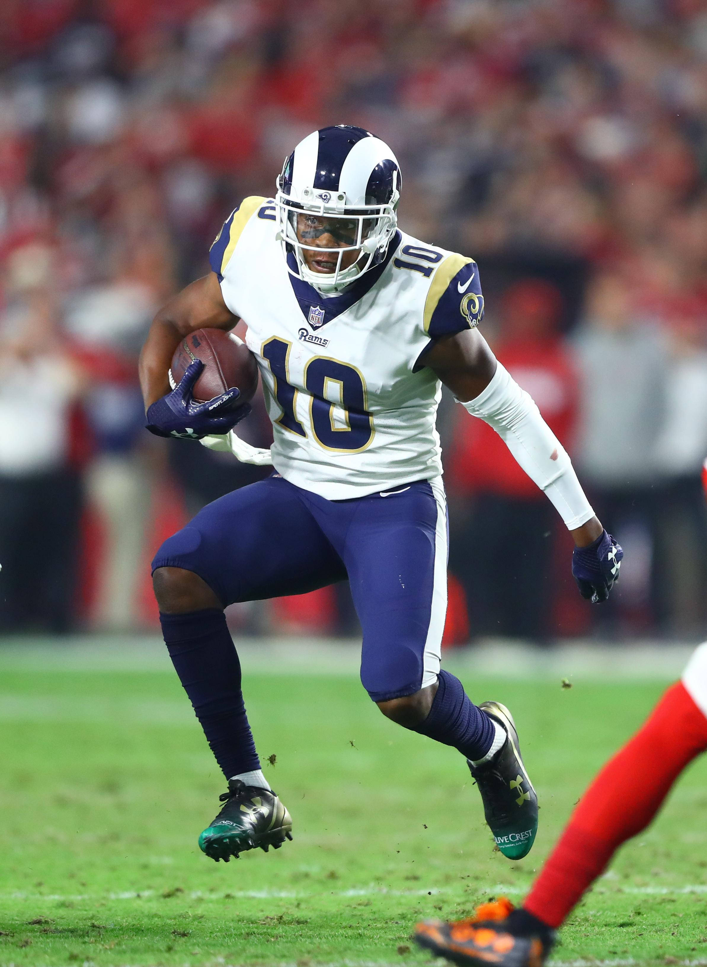 科珀·庫普 NFL 拉姆斯隊美式足球動作攝影 壁紙 — 一位身穿白色和紫色球衣的洛杉磯公羊隊美式足球員在夜間比賽中，在球場燈光下帶球衝刺。
