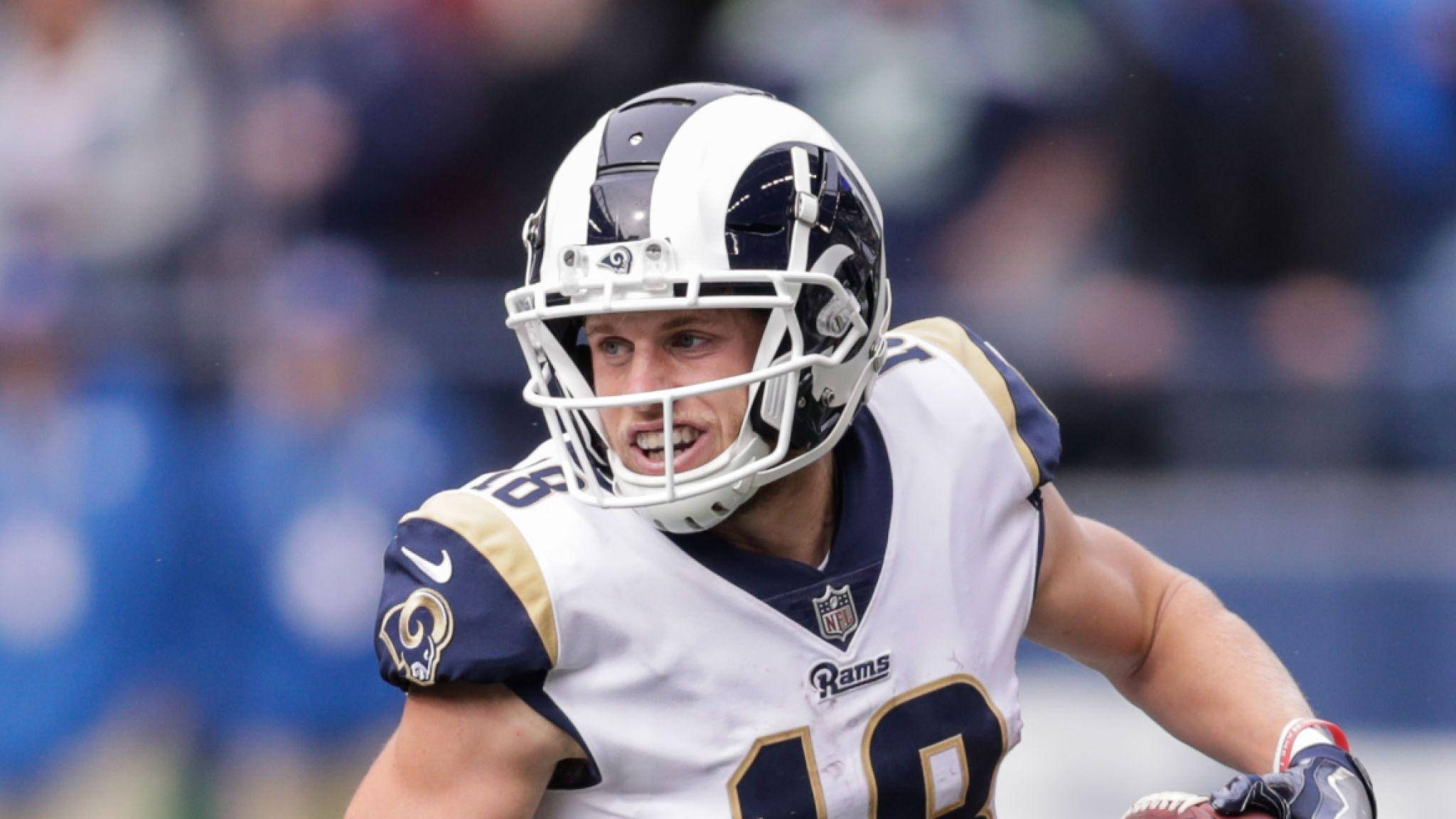 科珀·庫普 NFL 洛杉磯拉姆斯隊美式足球微笑攝影 壁紙 — 一名身穿白色和金色球衣的洛杉磯公羊美式足球員在日間比賽中決心衝刺。