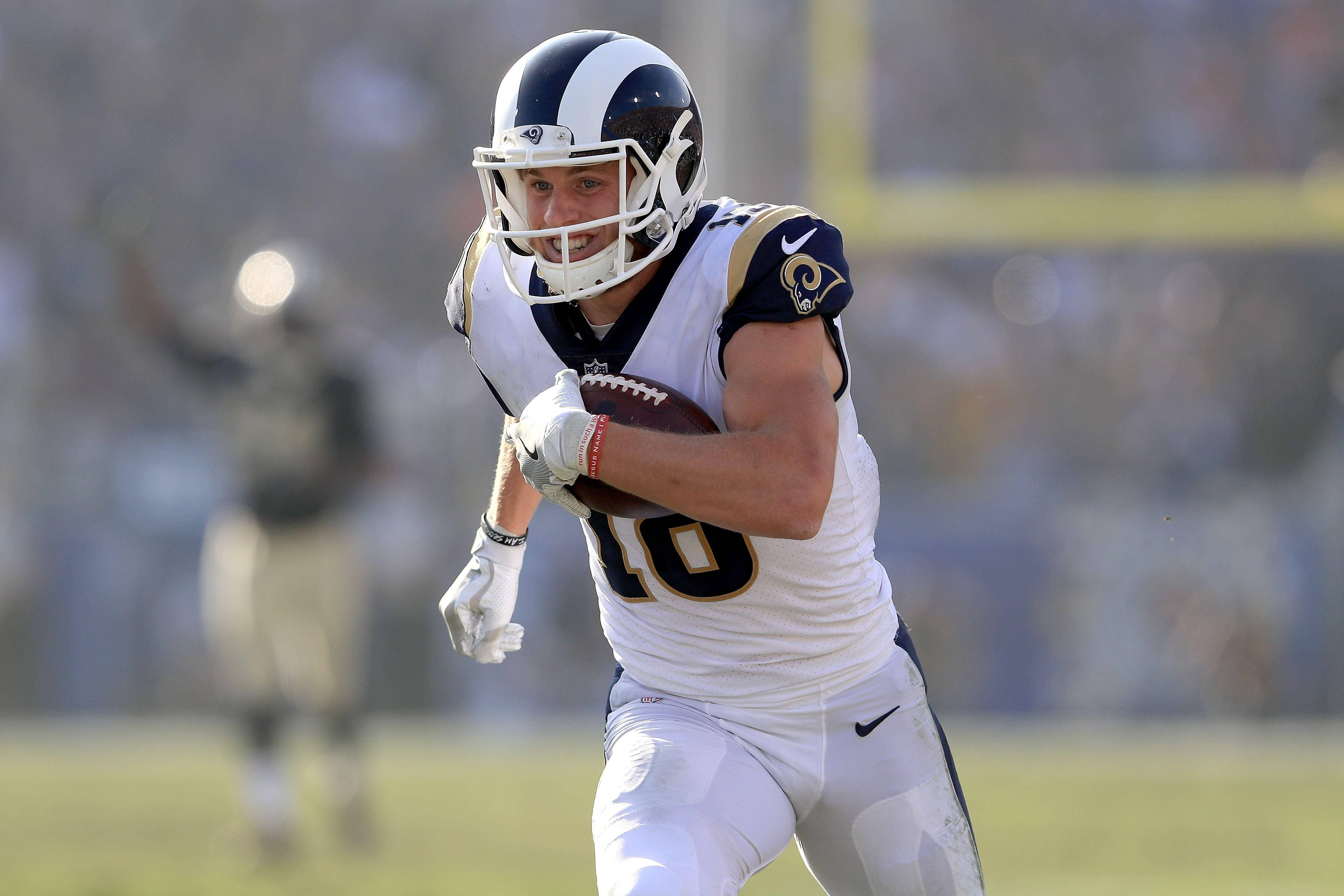 科珀·庫普 NFL 洛杉磯拉姆斯隊美式足球跑動攝影 壁紙 — 一名身穿白色Rams球衣的足球員在日間比賽中於草地上帶球衝刺。