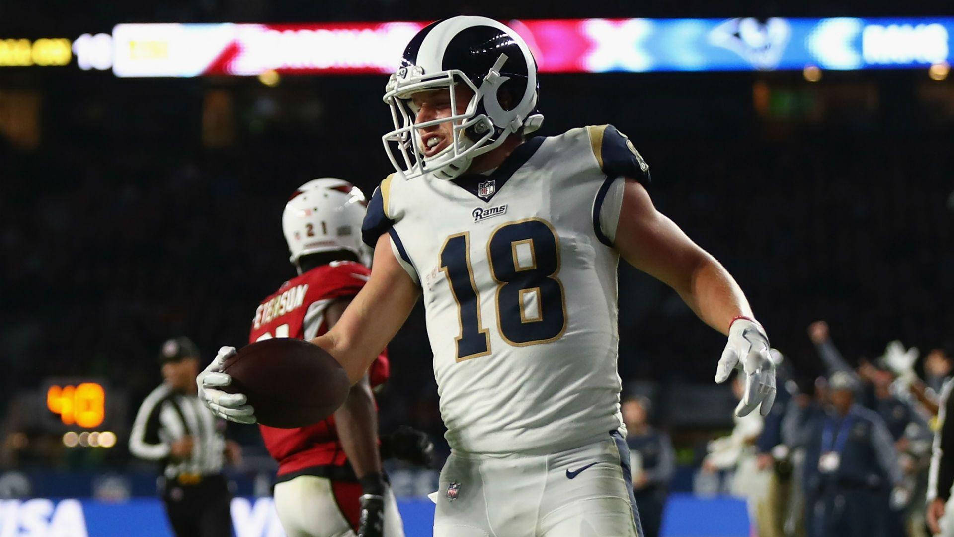 科珀·庫普 NFL 洛杉磯拉姆斯隊美式足球比賽攝影 壁紙 — 一位身穿白色18號球衣的洛杉磯公羊隊美式足球員在夜間球場燈光下拿著足球慶祝。
