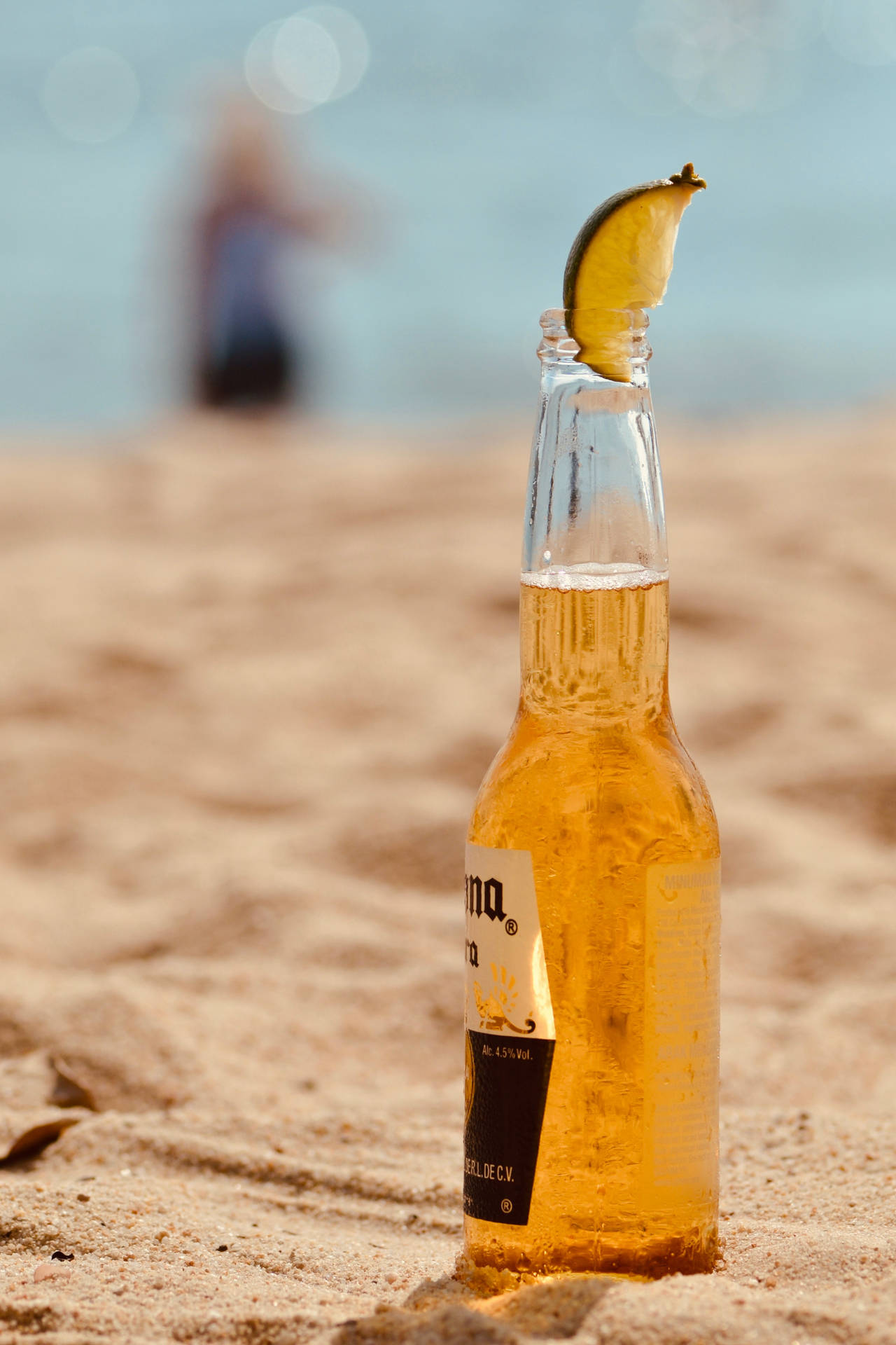 冰凍的Corona啤酒瓶配青檸角放在沙灘上，靠近海洋。