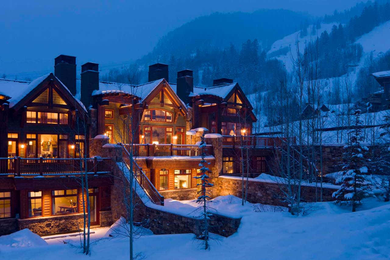 科羅拉多州阿斯彭的壯麗山景 壁紙 — 被雪覆蓋的山間小屋，溫暖發光的窗戶，坐落在冬日森林的暮色中。