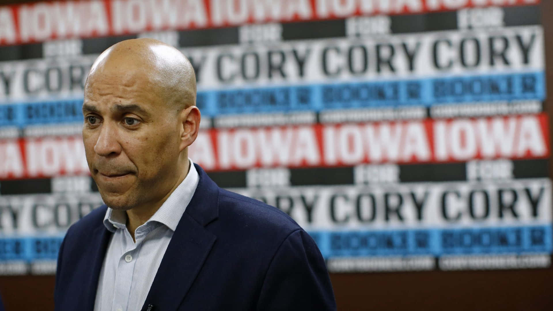 政治家Cory Booker在競選活動中，身後有重複的標語牌。