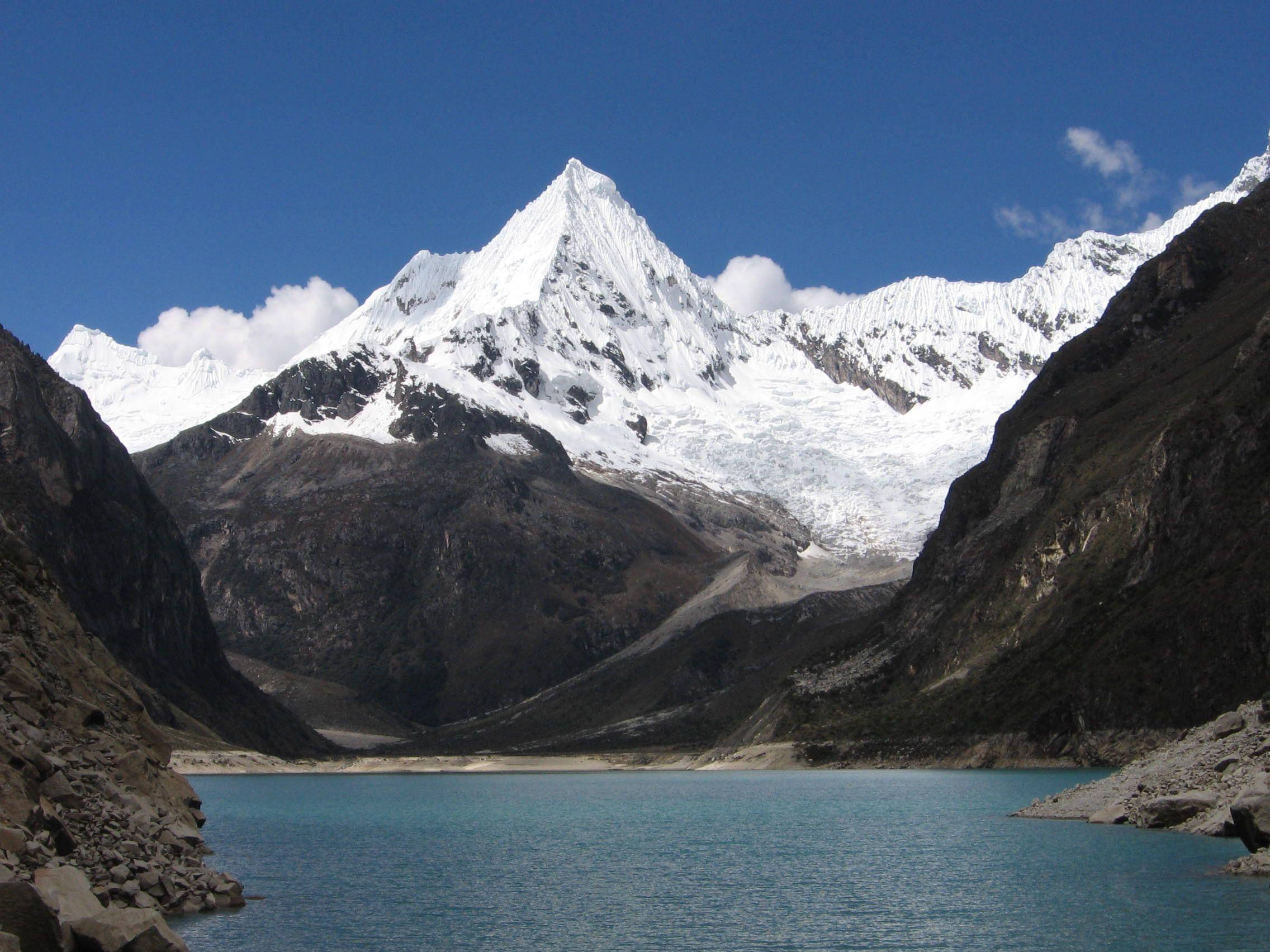 秘魯帕龍湖景觀 壁紙 — 寧靜的碧綠湖面映照著白雪覆蓋的山峰，天空湛藍，白雲點綴。