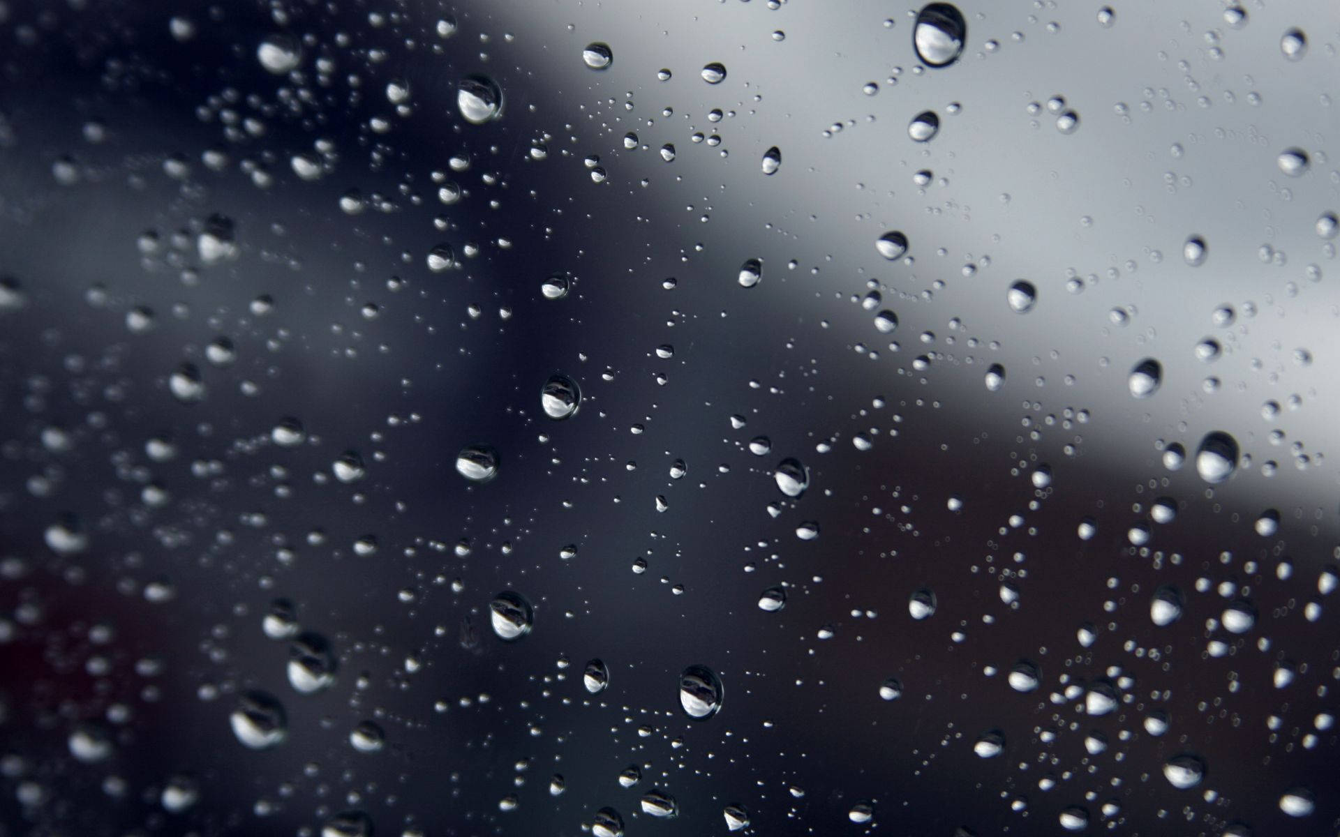 玻璃上雨滴的特寫，背景模糊