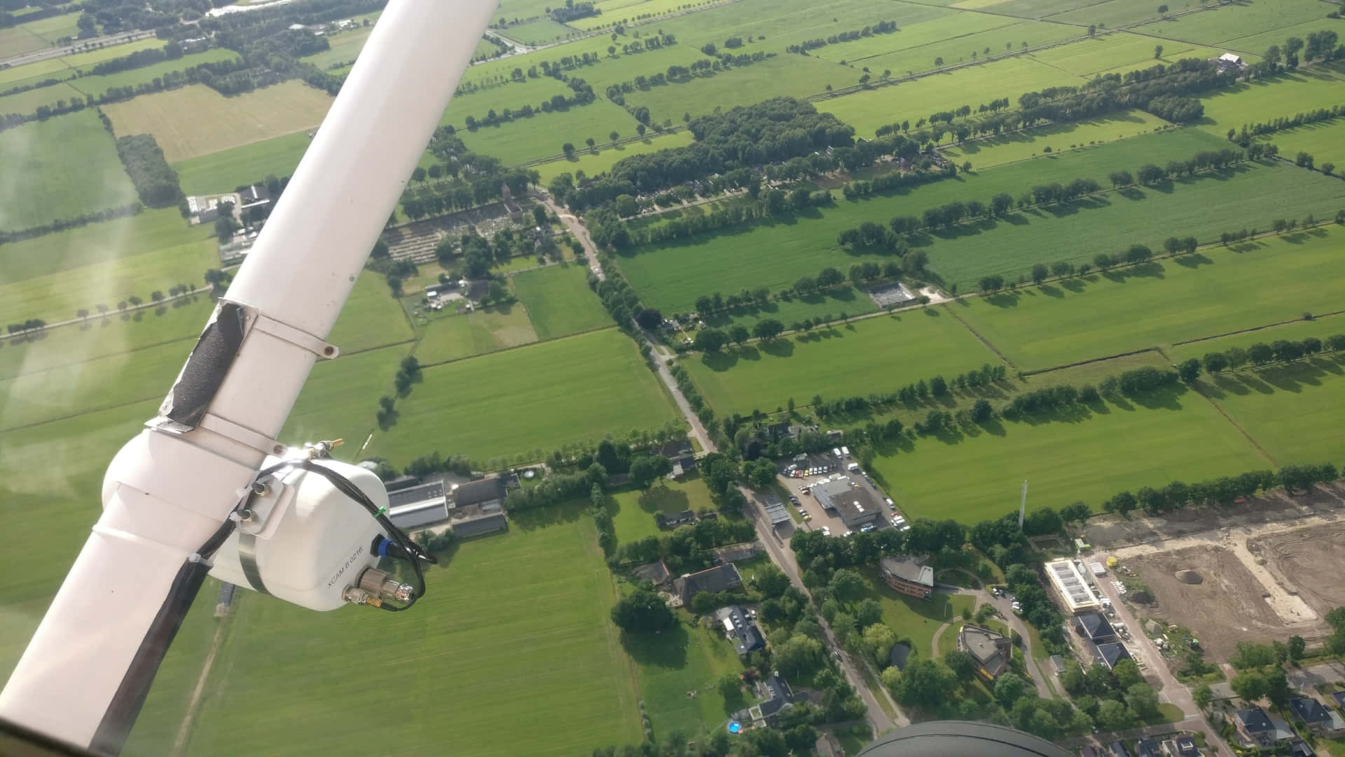 從飛機機翼俯瞰綠色農田同鄉村嘅高空視角。