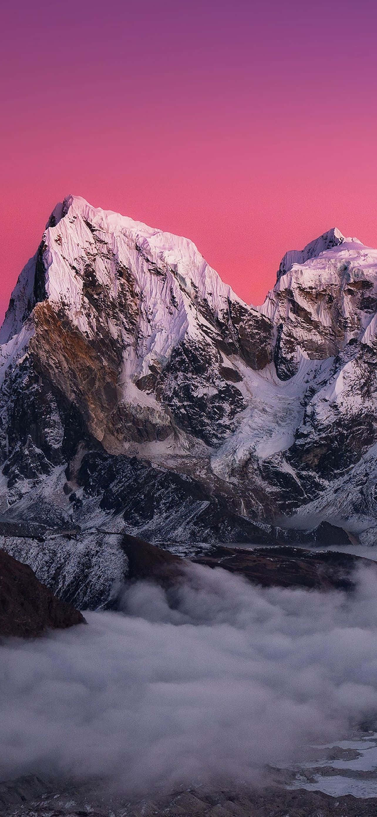 Mountain iPhone 桌布 壁紙 — 積雪的山峰刺穿雲海之上充滿活力的粉紅和紫色日落天空。